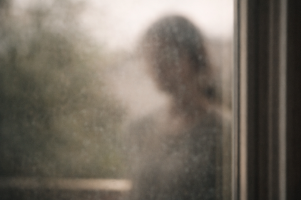 Reflet flou dans une vitre évoquant une présence difficile à identifier mais agissante